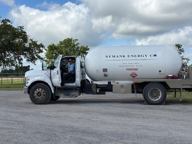 A man smiling while standing on the step of a propane delivery truck